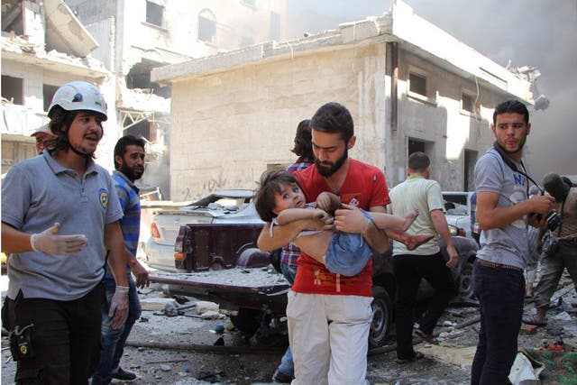A Syrian man carries a child at the scene of a reported air strike on the rebel-held northwestern city of Idlib on Saturday 10th September 2016 Getty Images