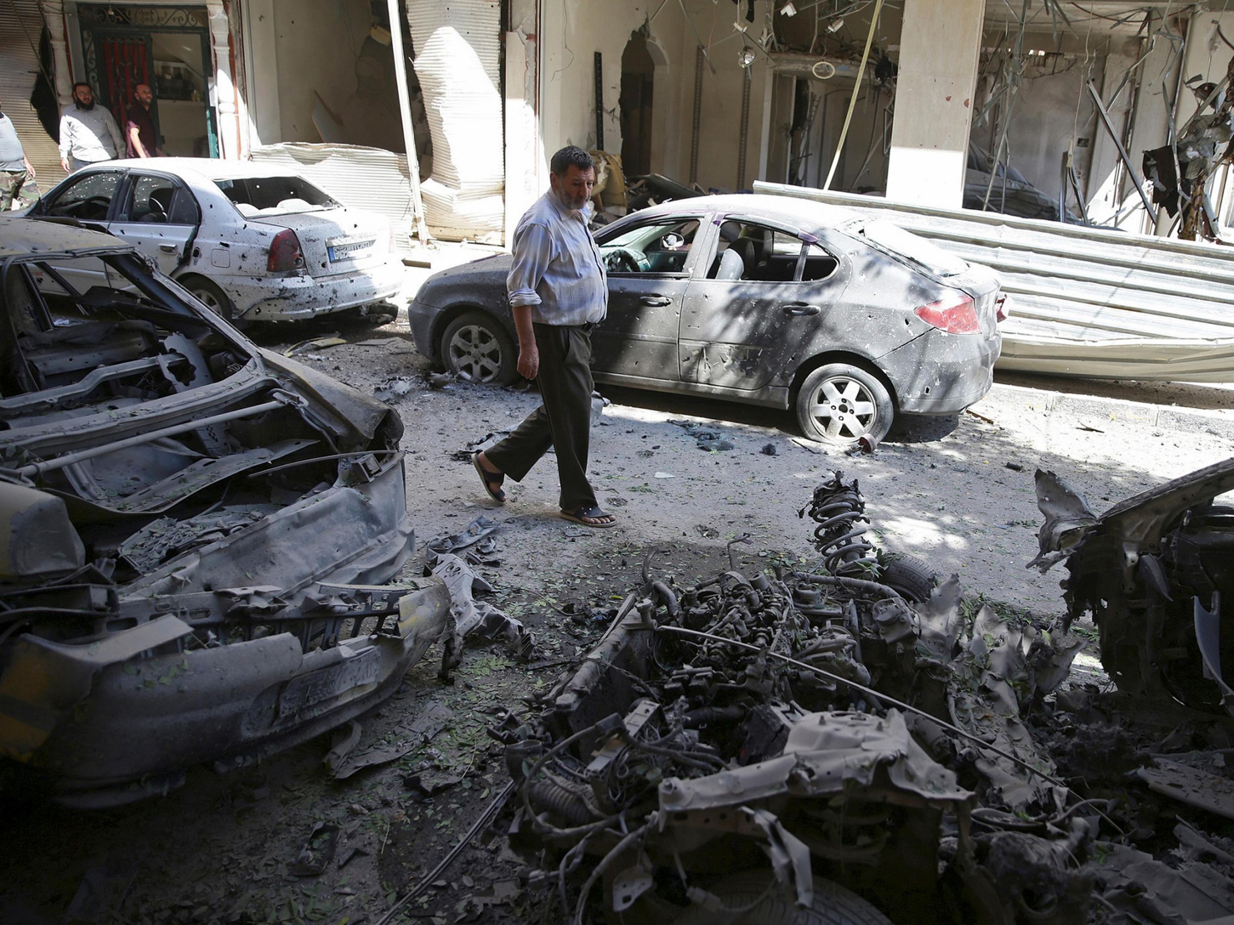 A man walks past damaged vehicles after an airstrike in the rebel held Douma neighborhood of Damascus on 9 September