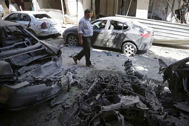 A man walks past damaged vehicles after an airstrike in the rebel held Douma neighborhood of Damascus on 9 September