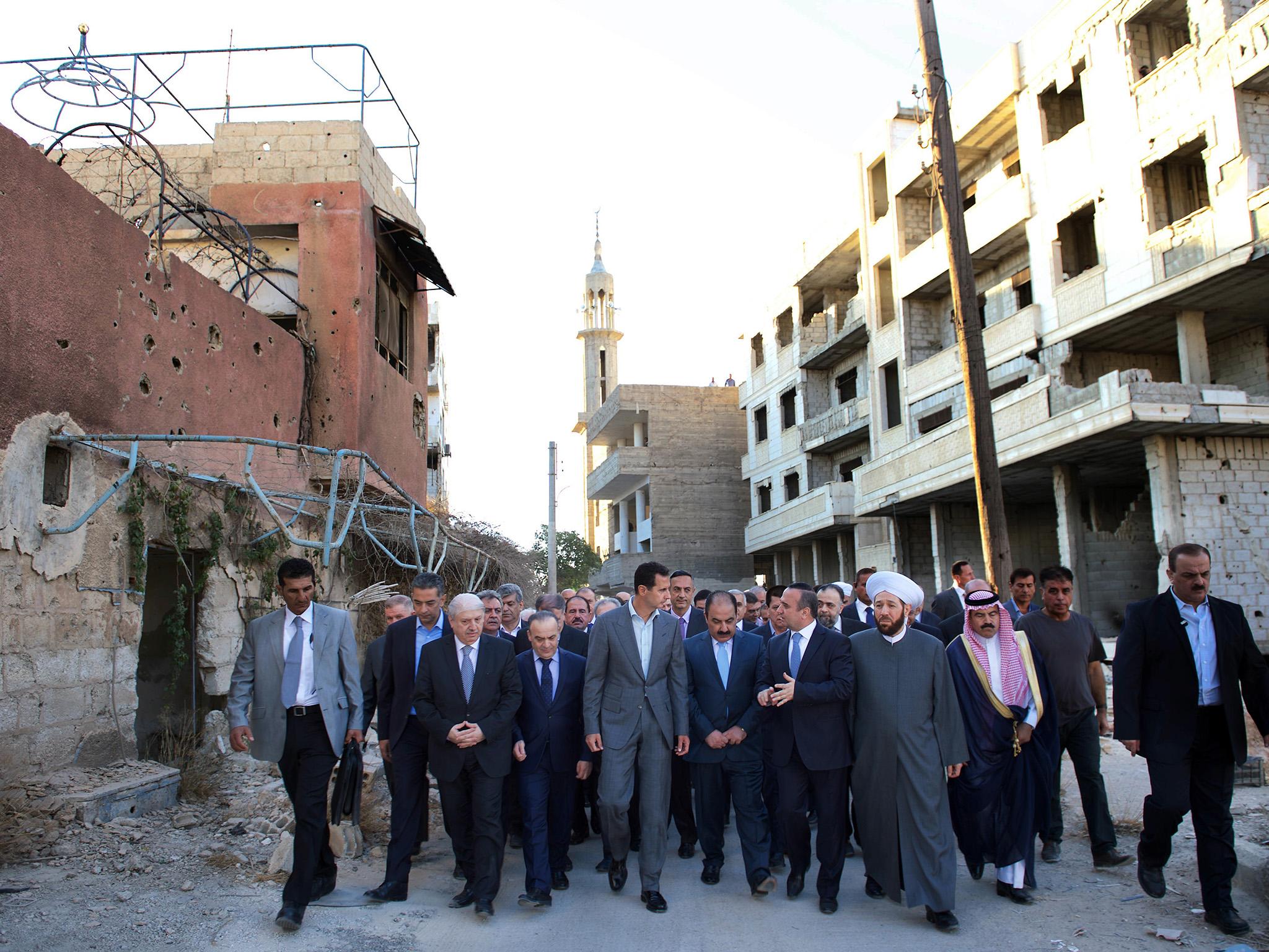 Syrian President Bashar al-Assad walking in a damaged Damascus suburb ahead of morning Eid Al-Adha prayers just hours ahead of the start of a ceasefire brokered by the US and Russia.