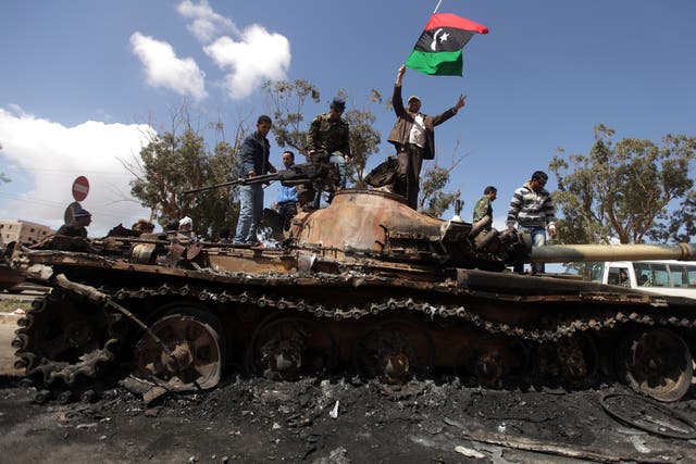 Rebels celebrate on top of a Gadaffi regime tank after air strikes near Benghazi in March 2011