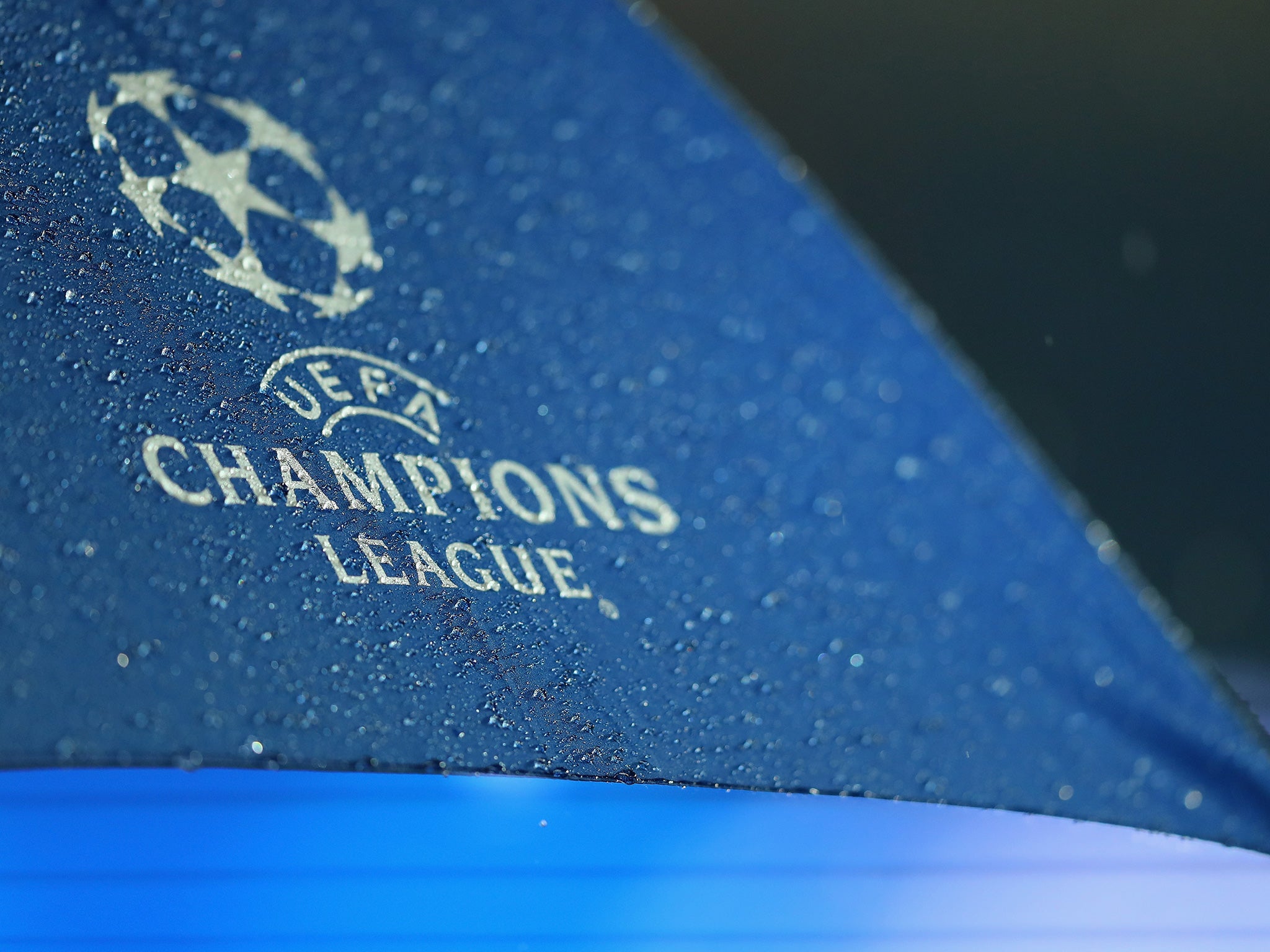 A branded Champions League umbrella catches raindrops at the Etihad