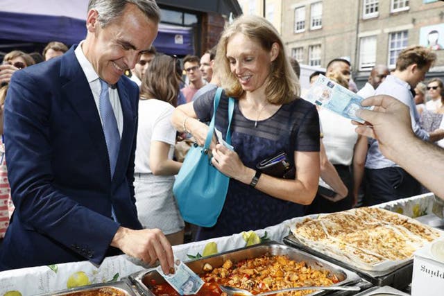 Bank of England Governor Mark Carney tests the new five pound note at a market in London