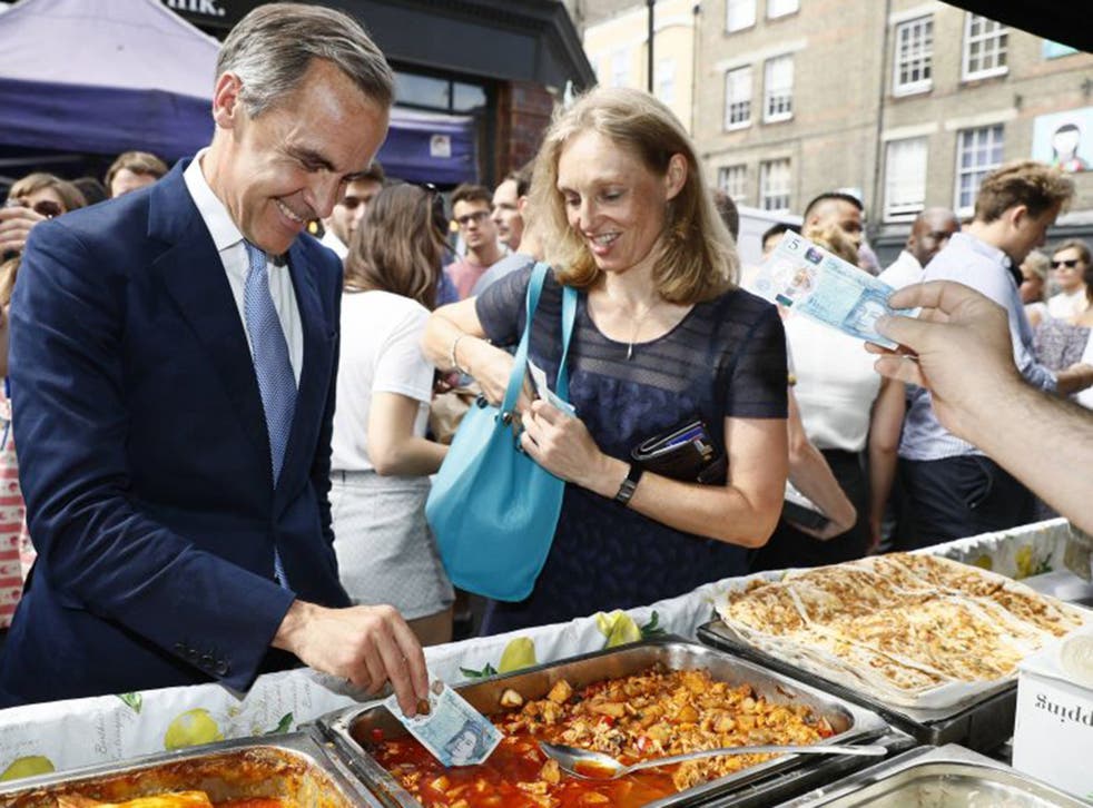 Bank of England Governor Mark Carney tests the new five pound note at a market in London