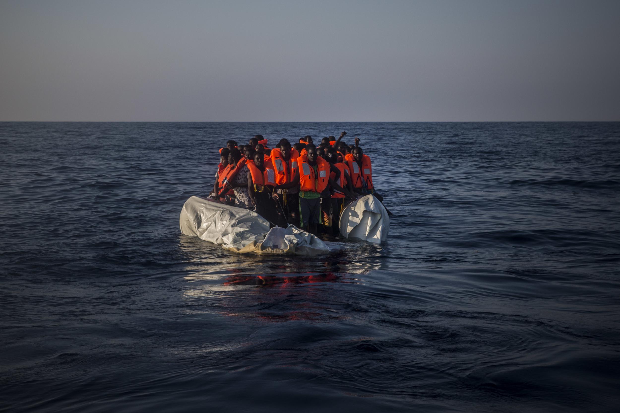African refugees aboard a partially punctured rubber boat await rescue on the Mediterranean Sea