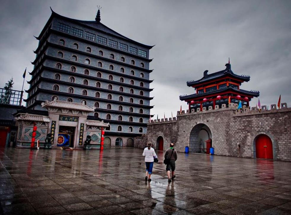 Tourists wander past the Dragon Gate hotel, which has remained unopened since it was first built in 2004