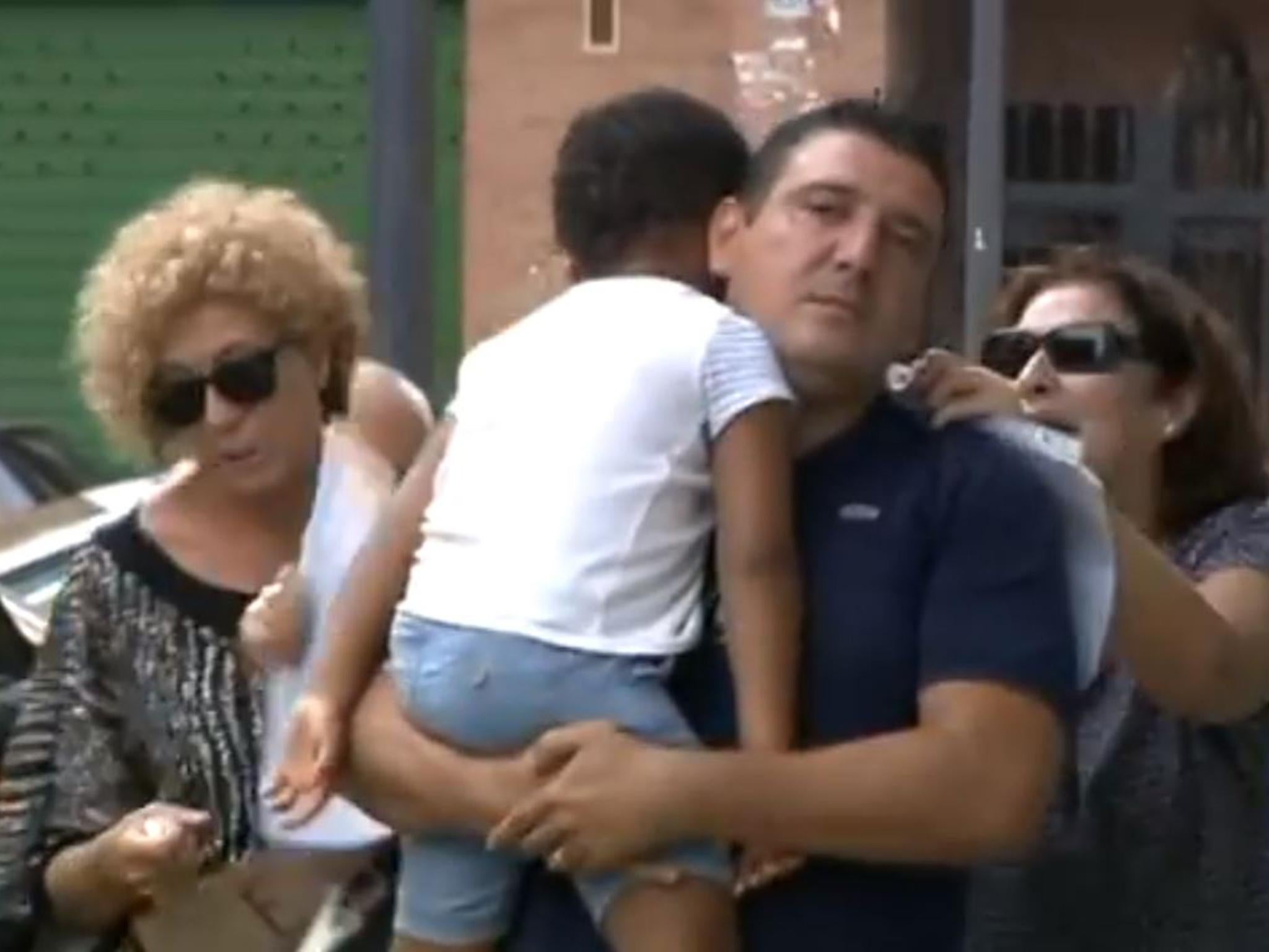 Four-year-old Joan is carried to the police station in Valencia by his adopted father Albert