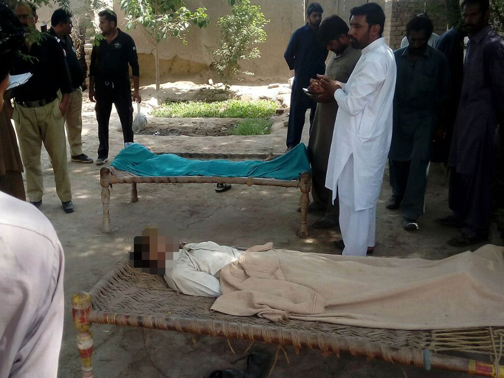 Pakistani police officials stand around the bodies of a woman and her alleged boyfriend who were hanged to death by the woman's father, brother and husband in the village of Chak 56, around 55 kilometres northeast of the central city of Multan, 15 September, 2016