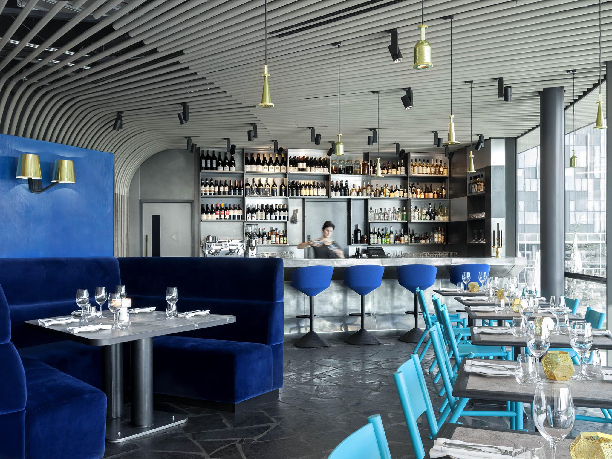 Tones of blue contrast the grey stone tables and Tom Dixon gold lights