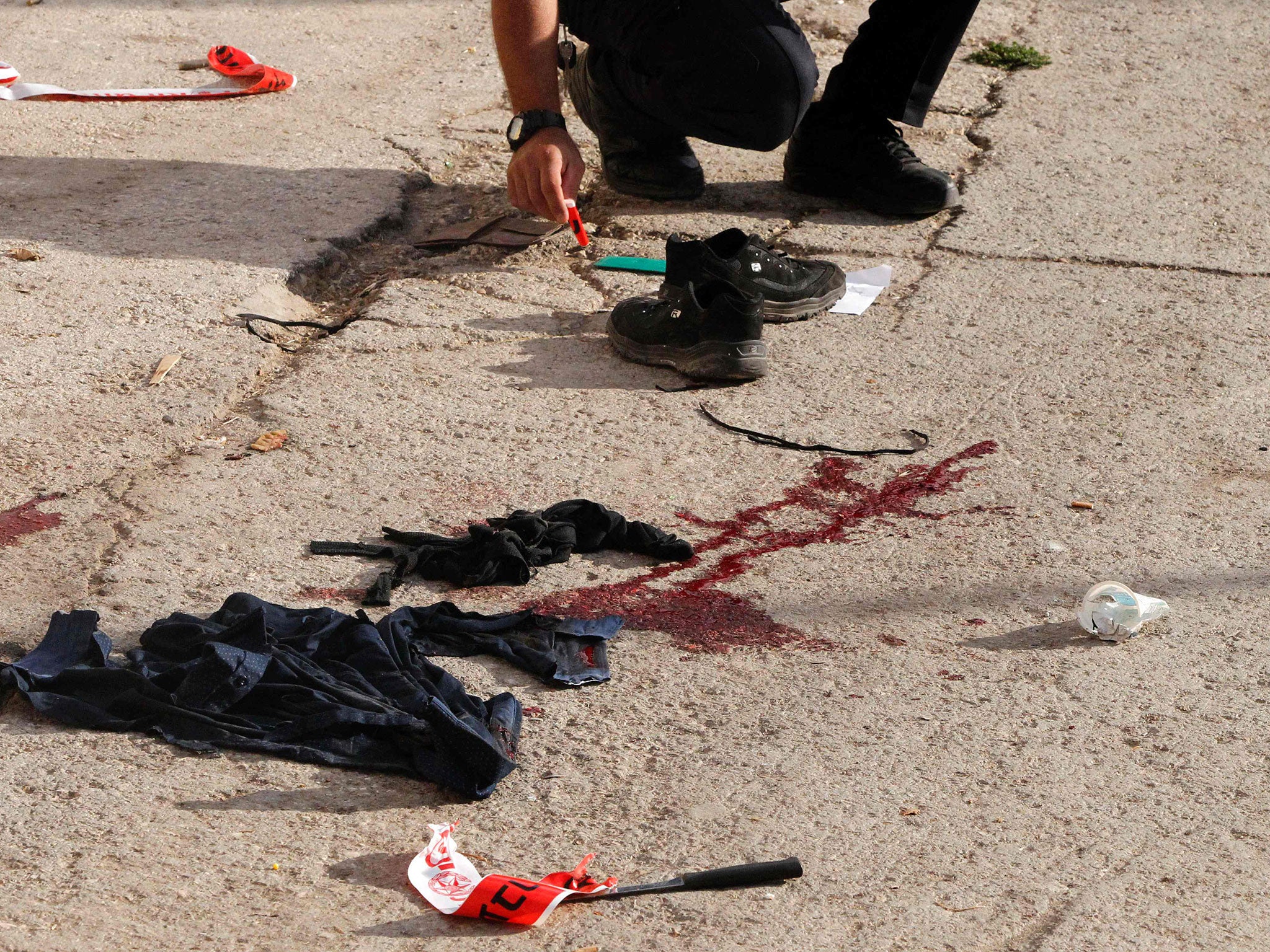 Israeli forensic police at the scene of a stabbing attack where a Palestinian was shot dead in the West Bank city of Hebron on 17 September