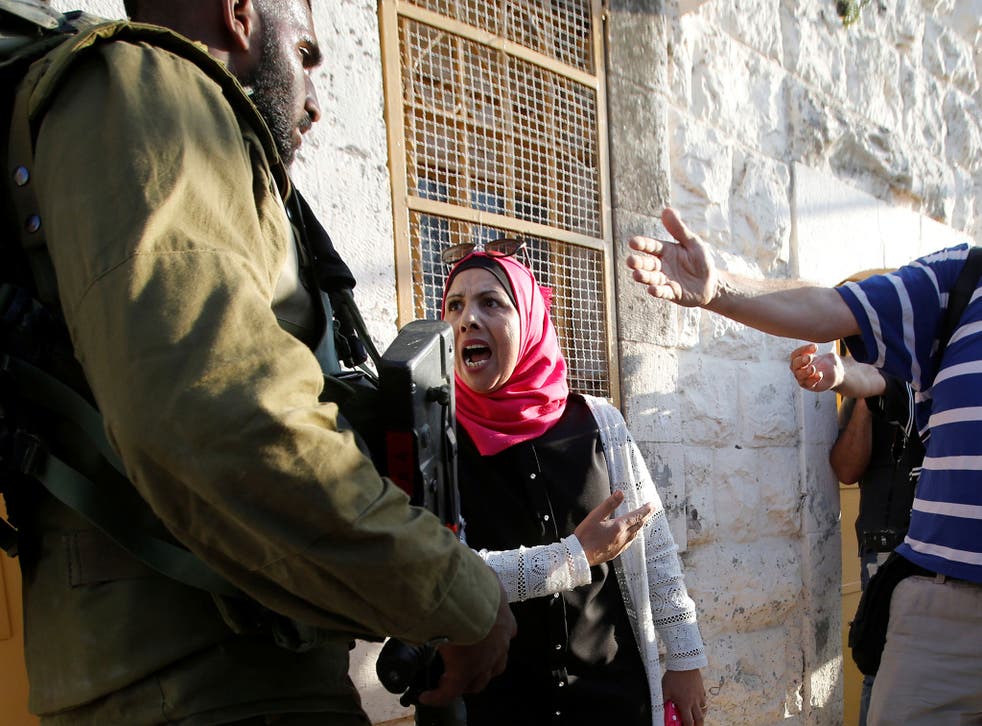 A Palestinian woman argues with an Israeli soldier near the scene of an attack in Tel Rumeida in the West Bank city of Hebron on 16 September