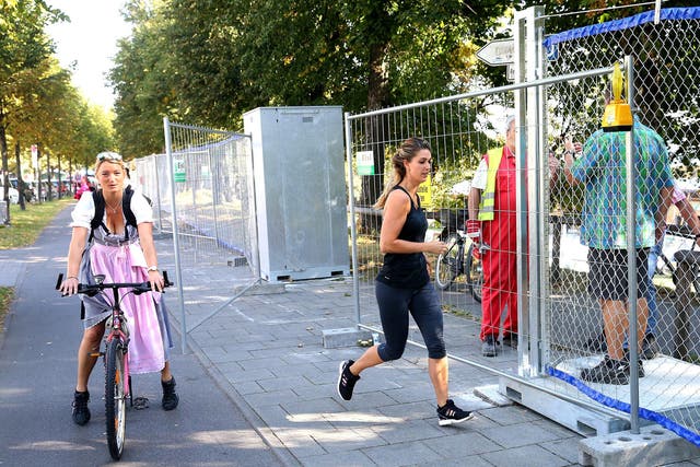 Waitress Josefine passes the new security fence on her way to the Theresienwiese in Munich, Germany