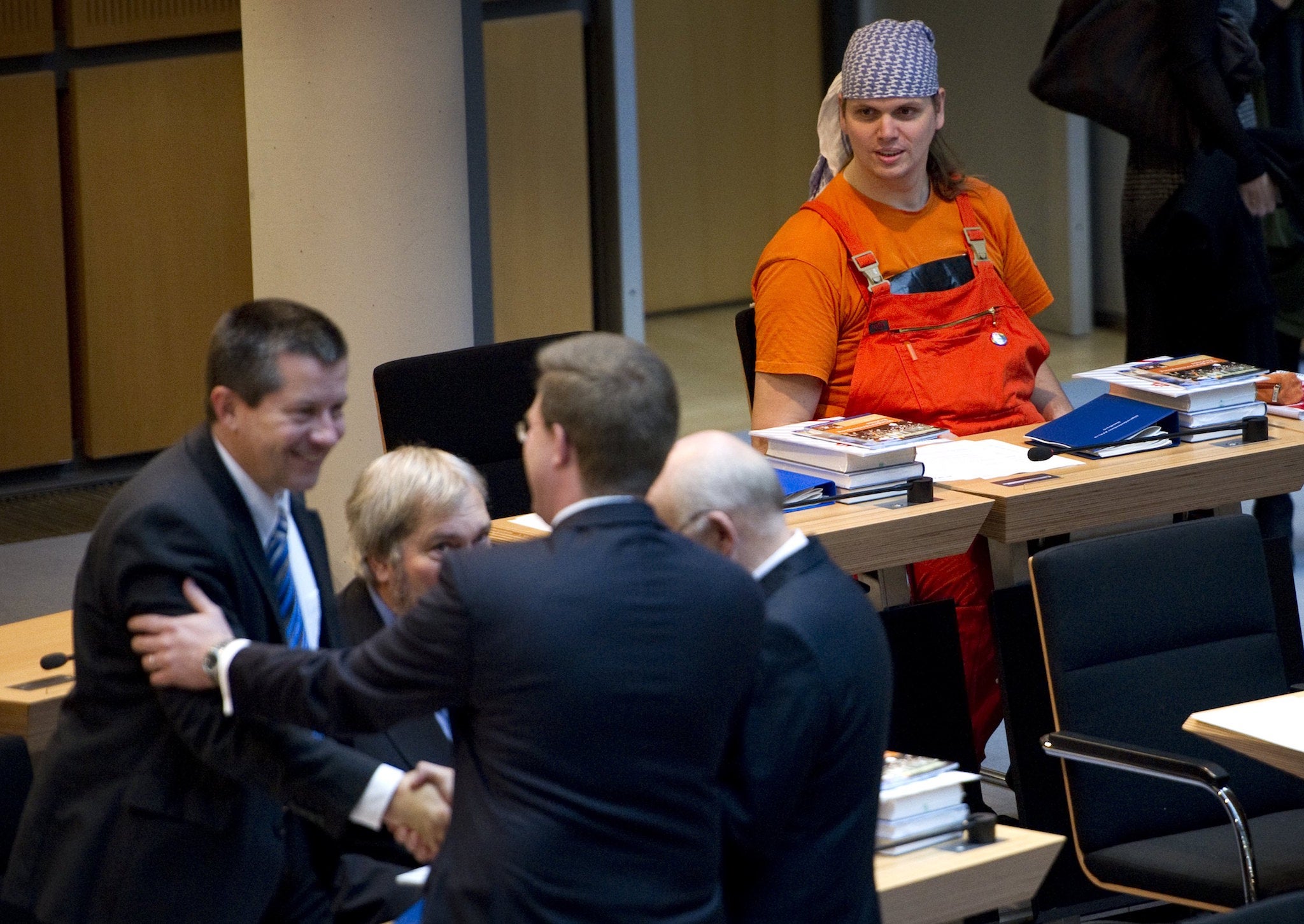 Mr Claus-Brunner (R) watches colleagues from other parties greet each other prior to the first sitting of the Berlin parliament on October 27, 2011. He stood out for his appearance in parliament and was at times a controversial figure