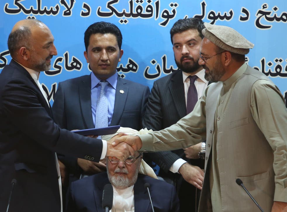 Afghanistan national security adviser Mohammad Hanif Atmar, left, and Amin Karim, representative of Gulbuddin Hekmatyar, right, shake hands after signing the power-sharing deal