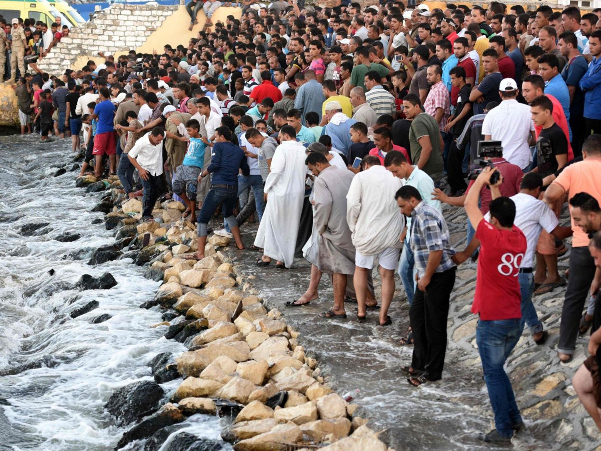 Egyptians stand on the shore as they wait for the recovery of bodies, during a search operation after a boat carrying migrants capsized in the Mediterranean, along the shore in the Egyptian port city of Rosetta on 22 September, 2016