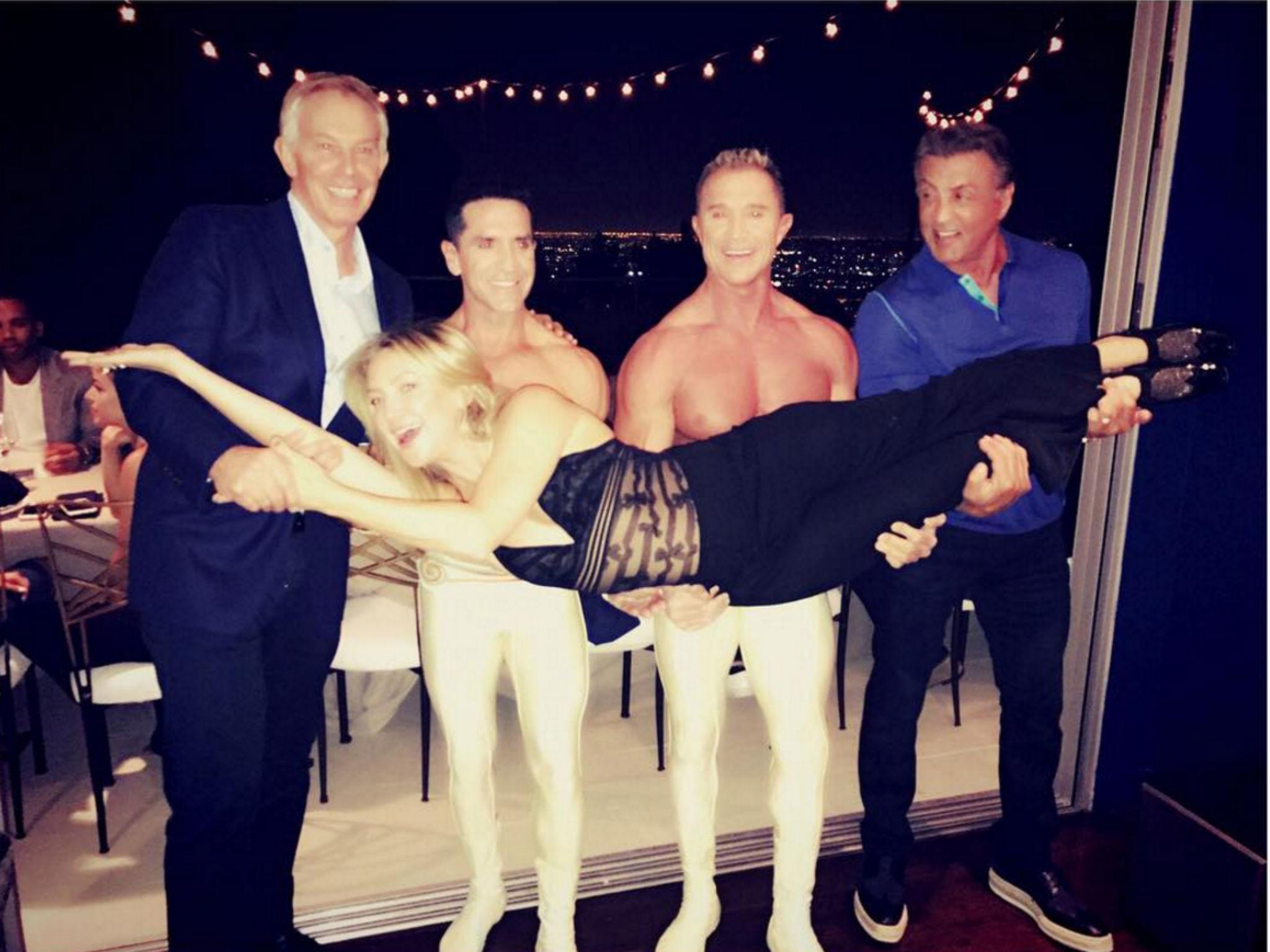 Tony Blair, two Cirque du Soleil performers and Sylvester Stallone hold up Kate Hudson