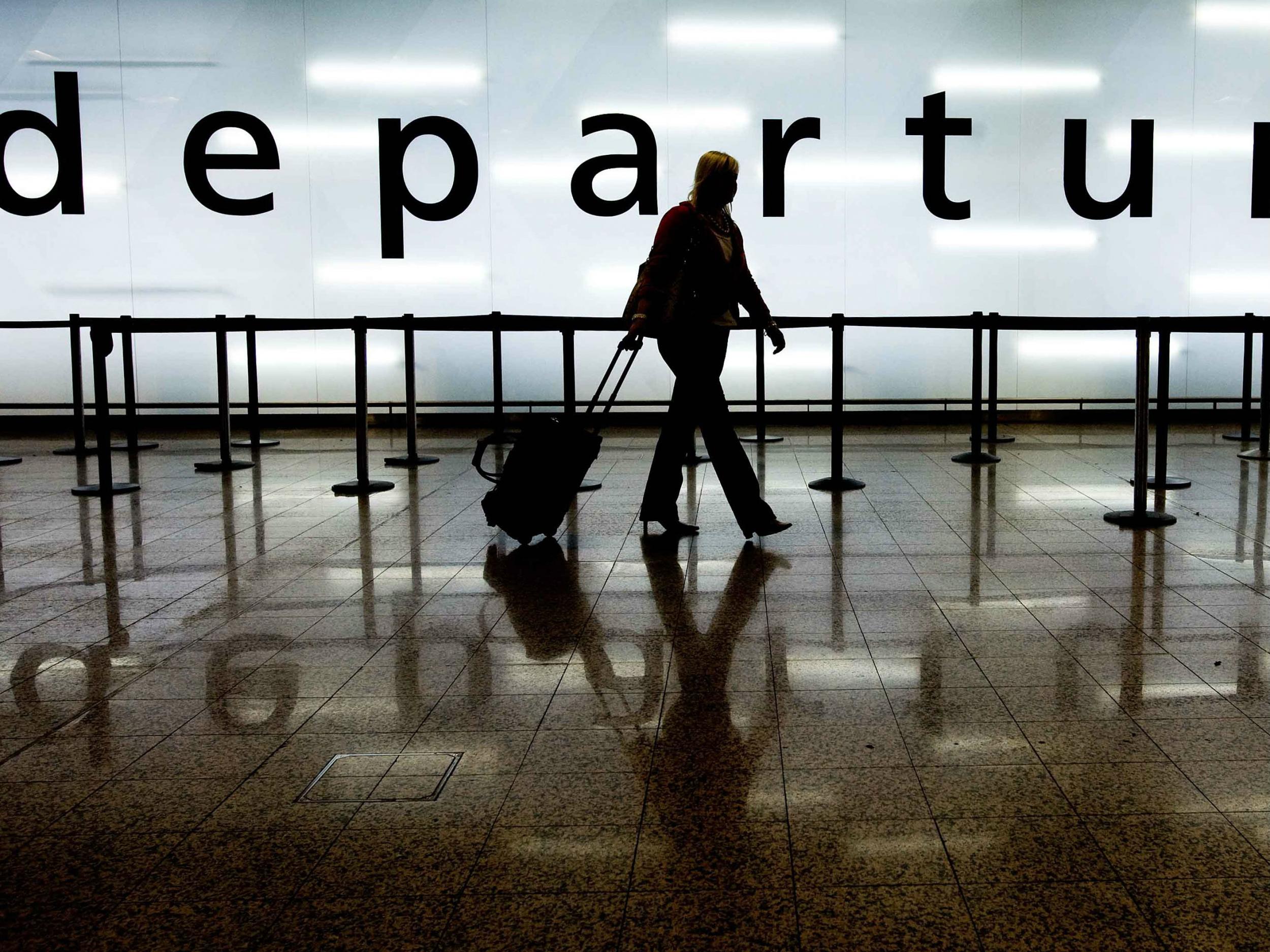A woman pulls her suitcase as she walks through the departures area of Glasgow Airport in Glasgow