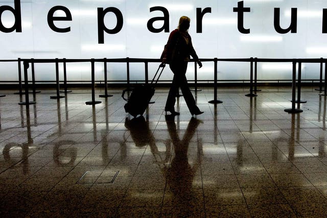 A woman pulls her suitcase as she walks through the departures area of Glasgow Airport in Glasgow