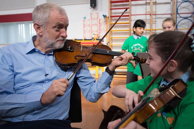 The Labour leader is given a violin lesson by 10 year old Jessica Kelly during a visit to Faith Primary School in Liverpool today