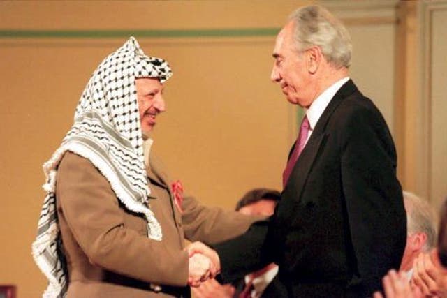 PLO chairman Yasser Arafat shakes hands with then-Israeli Foreign Minister Shimon Peres in 1994