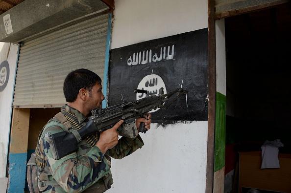An Afghan soldier points his gun at an Islamic State group banner as he patrols during ongoing clashes in eastern Nangarhar province on July 26, 2016.