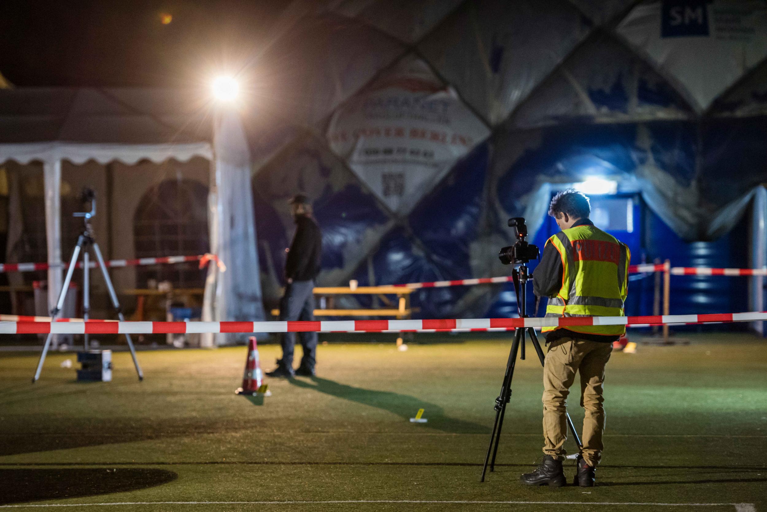Police officers investigate the scene of the shooting in front of an air-inflated shelter for refugees in Berlin