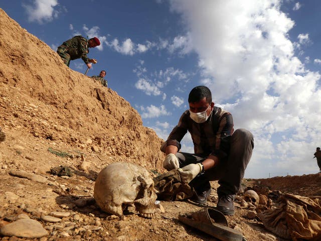 An Iraqi man inspects the remains of Yazidi people killed by Isis and buried in a mass grave near the village of Sinuni, in the northwestern Sinjar area
