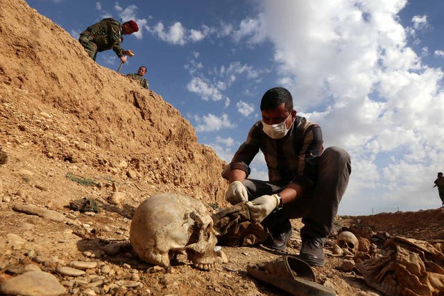 An Iraqi man inspects the remains of Yazidi people killed by Isis and buried in a mass grave near the village of Sinuni, in the northwestern Sinjar area