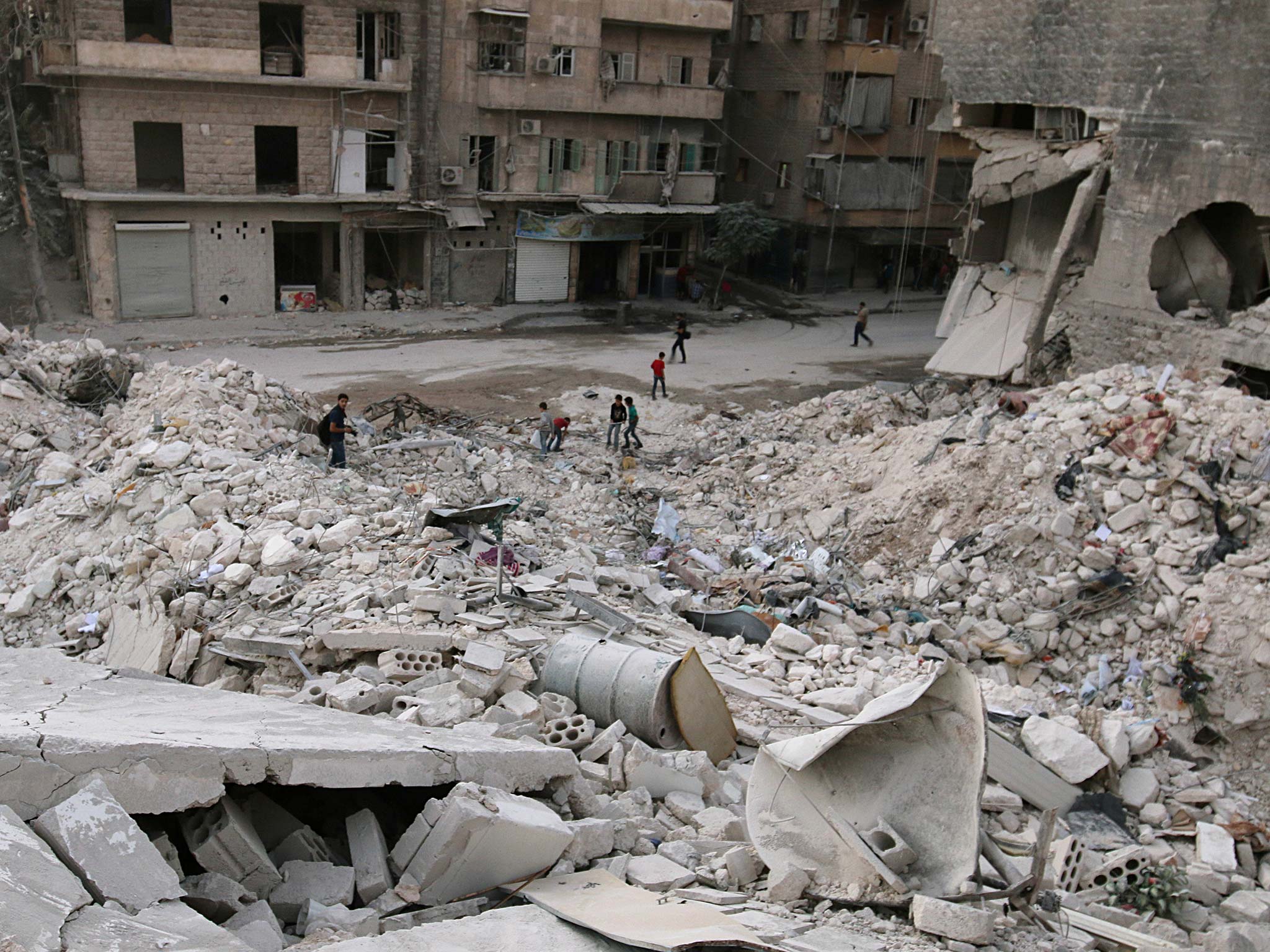 People walk on the rubble of damaged buildings in the rebel held area of al-Kalaseh in Aleppo on 29 September