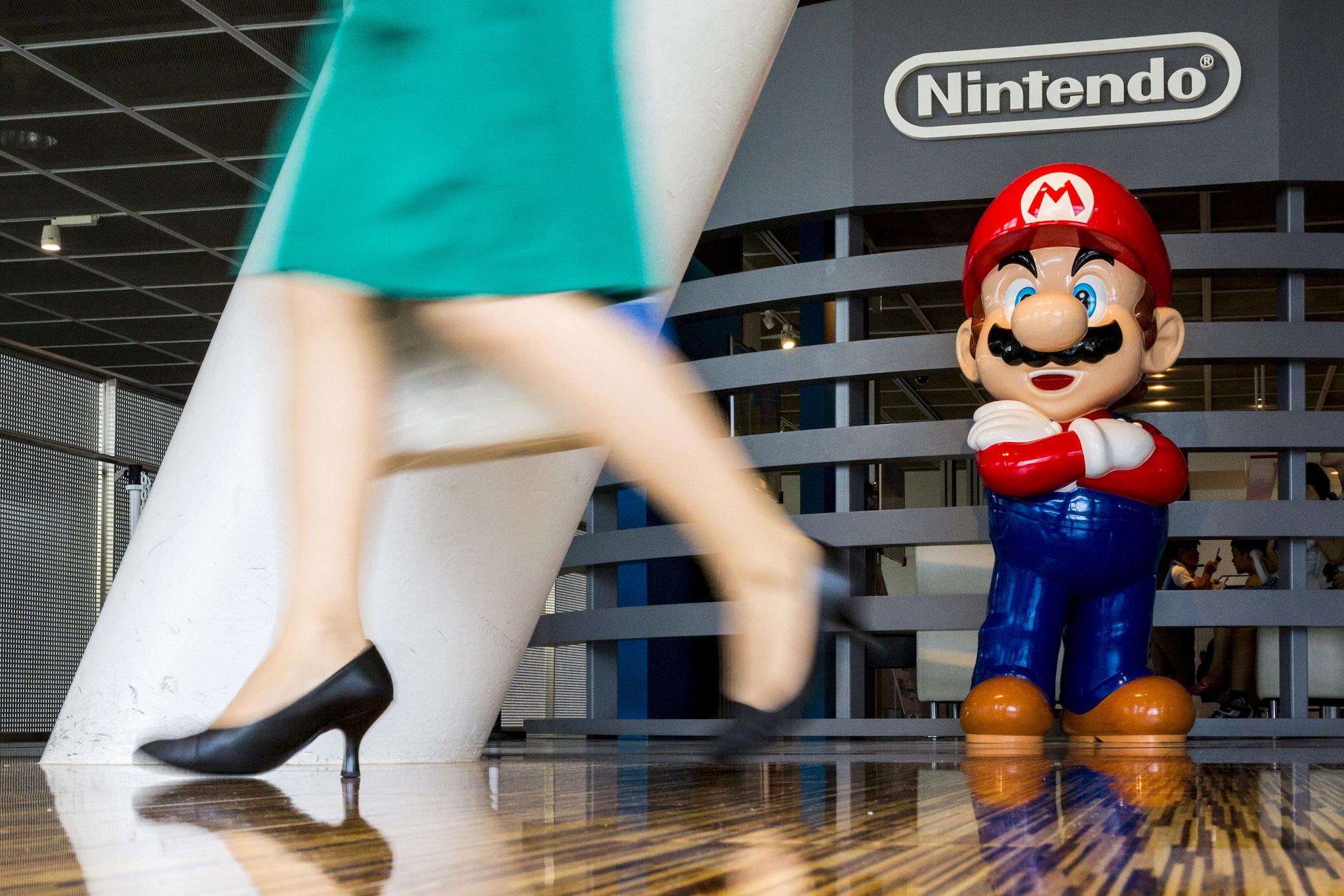 A woman walks past a figure of "Mario", a character in Nintendo's "Mario Bros." video games, at a Nintendo centre in Tokyo July 29, 2015