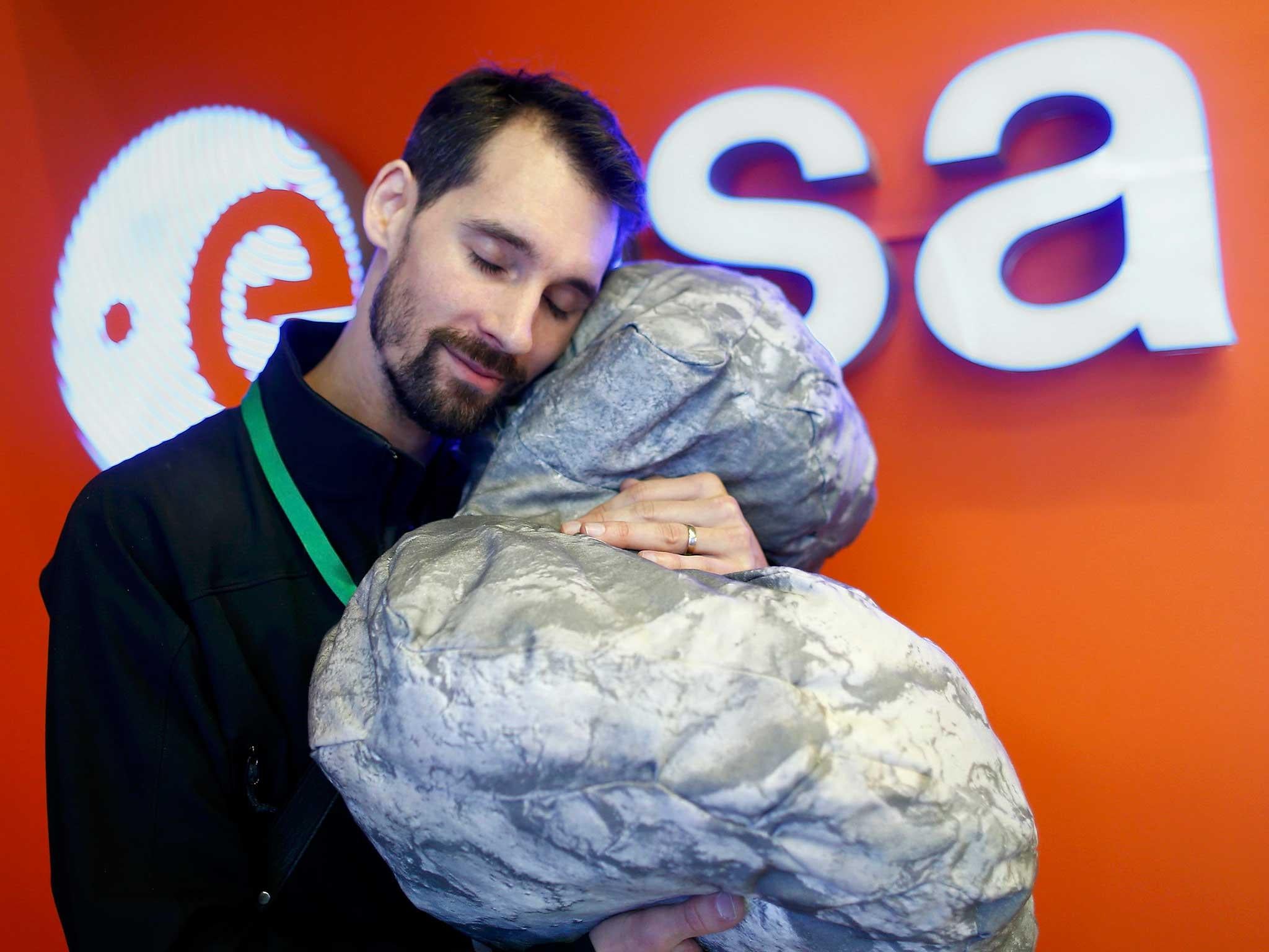 European Space Agency's (ESA) staff Mattial Malmer poses with a comet 67P/ Churyumov-Gerasimenko shape pillow at the European Space Agency's (ESA) headquarters in Darmstadt, as the the Rosetta spacecraft is nearing the end of its historic, 12-year comet chase