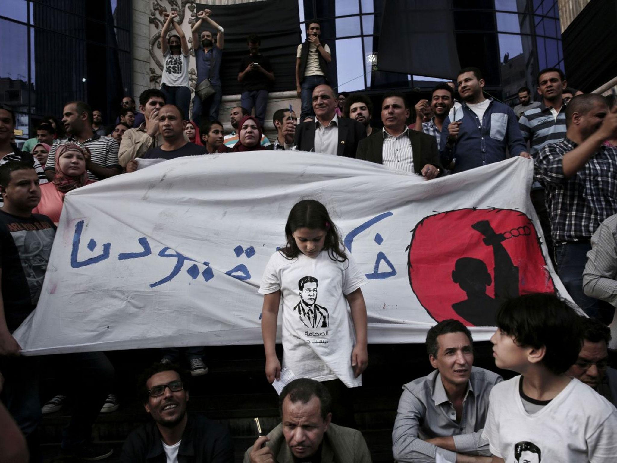 A girl stands in front of a banner with Arabic that reads 'remove our shackles' during a protest to mark World Press Freedom Day in front of the Press Syndicate in Cairo, 3 May, 2016