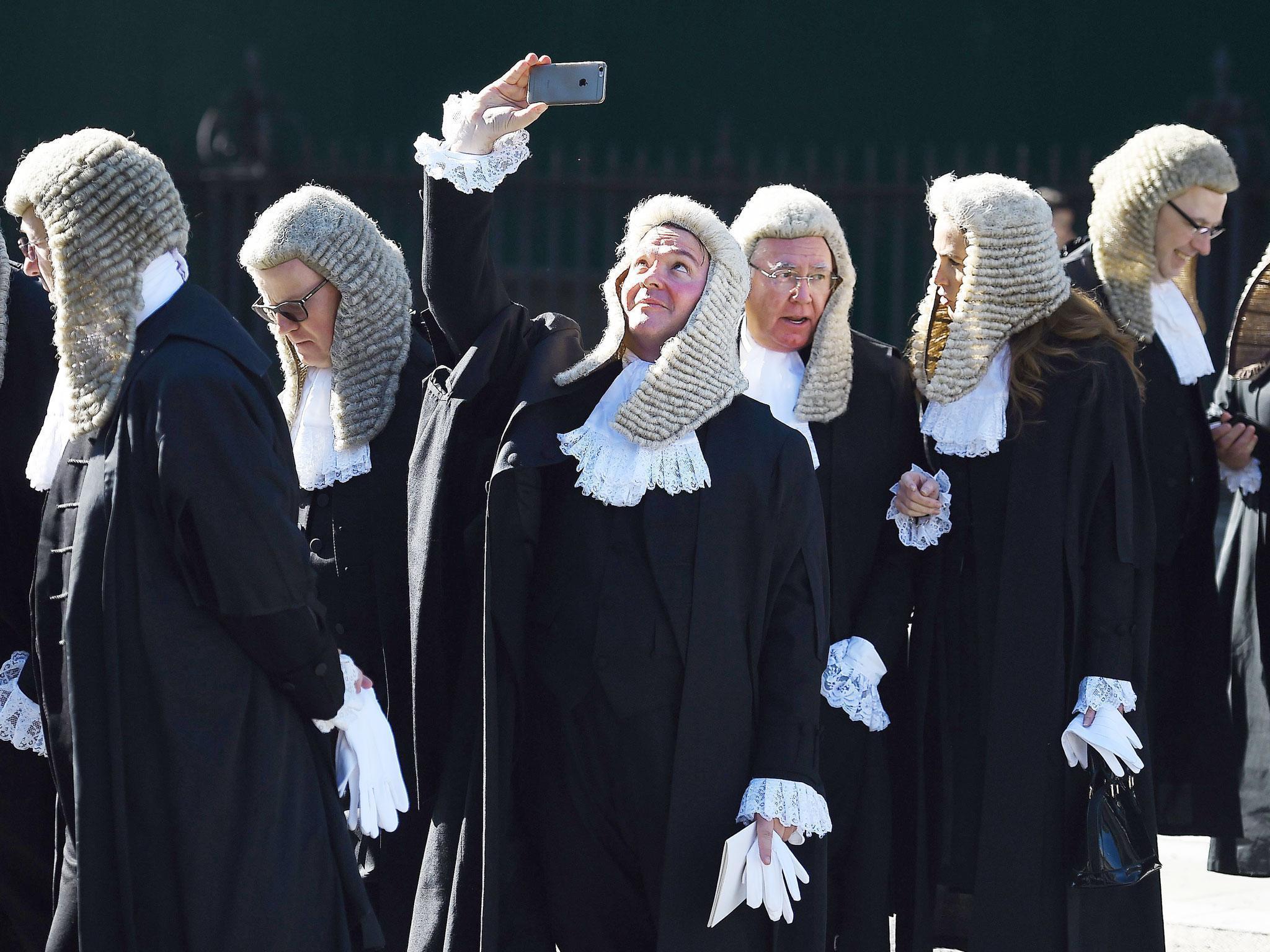 A judge takes a selfie as he follows a procession of judges in to the houses of parliament in London