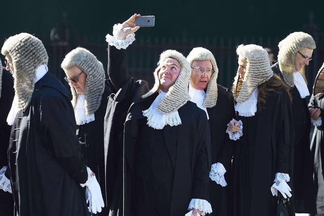 A judge takes a selfie as he follows a procession of judges in to the houses of parliament in London