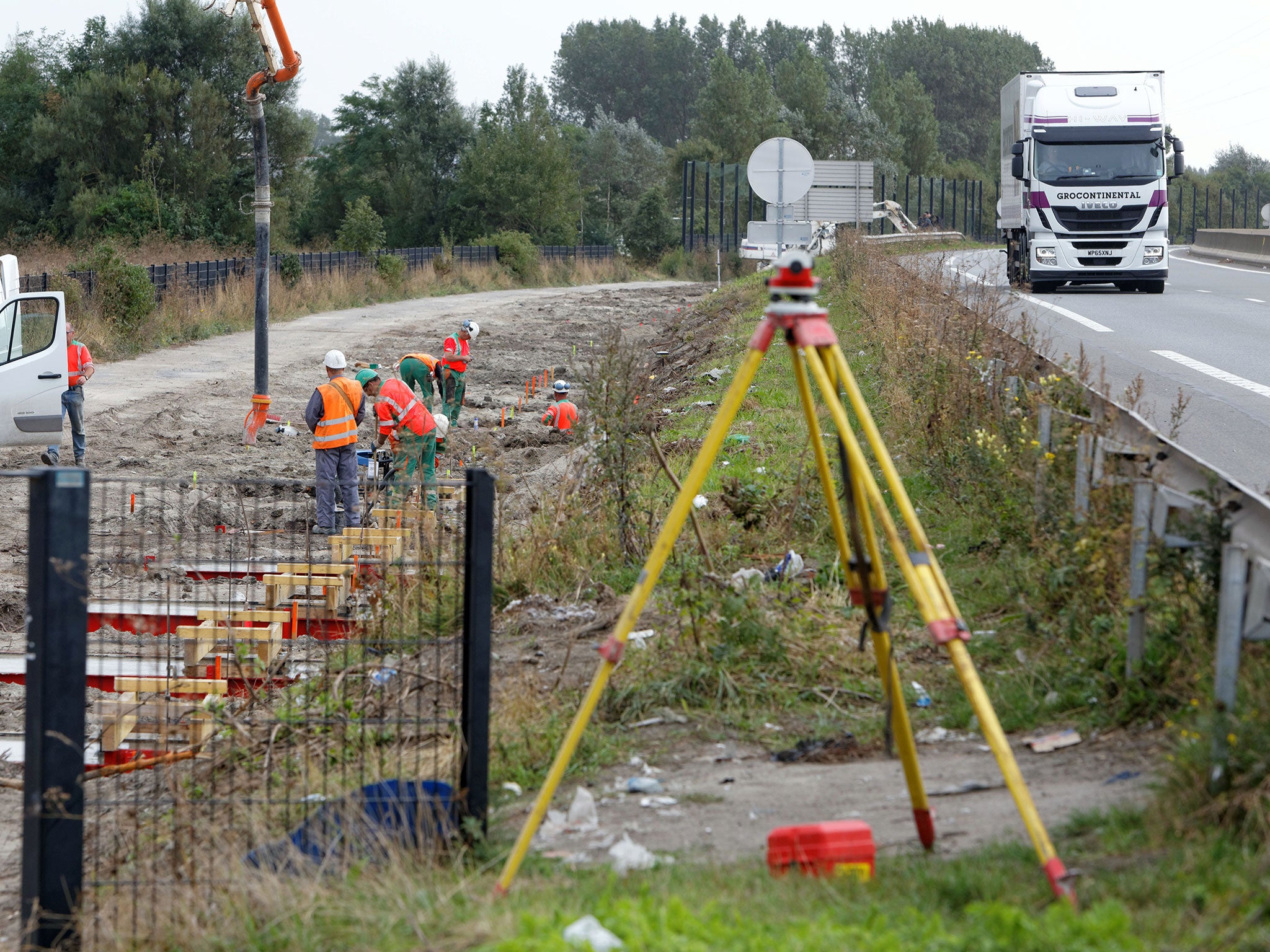 Workers dig foundations of a wall near Calais migrant Jungle camp along the road leading to the harbour of Calais on September 26, 2016 in France