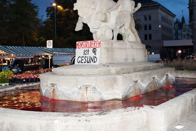 The fountains were dyed with food colouring shortly before dawn. The sign reads "Menstruation is healthy"