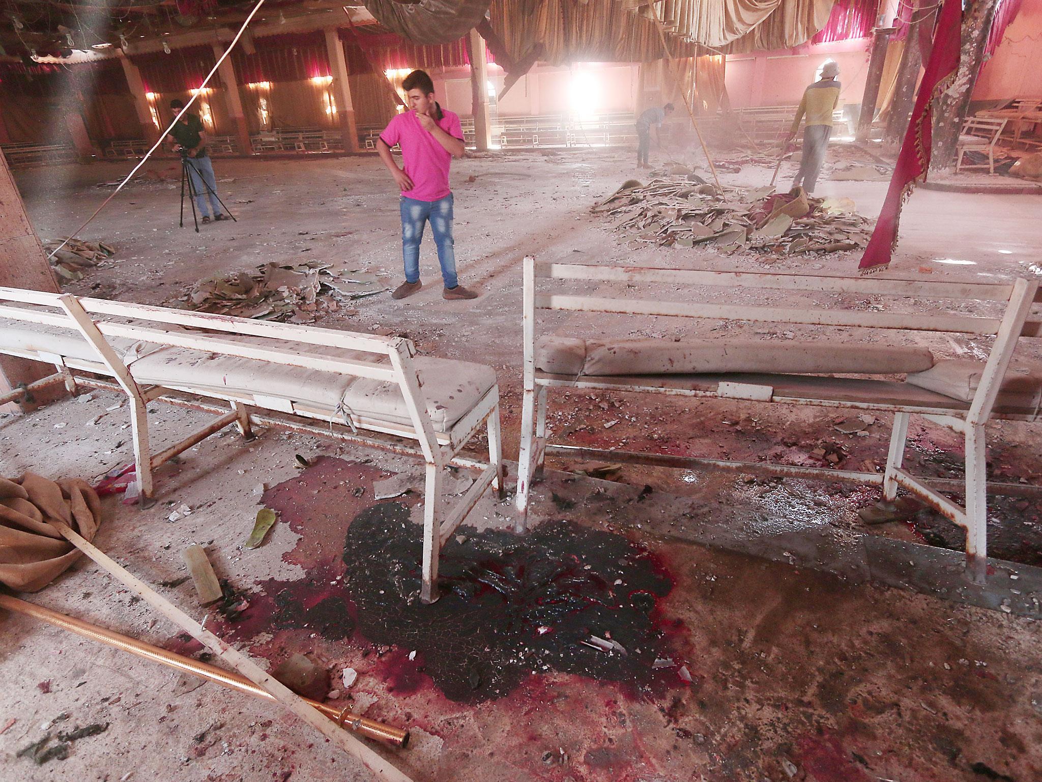 Blood stains the ground while workers remove rubble in a damaged wedding hall after a suicide attack on a Kurdish wedding in Hasaka city, Syria