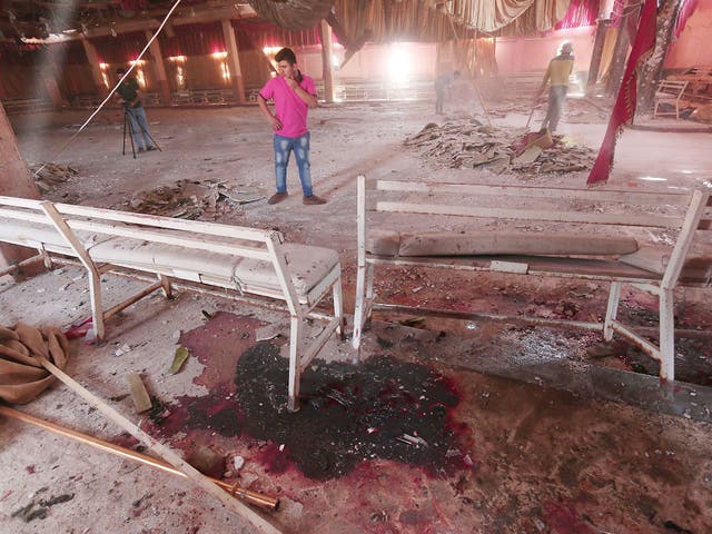 Blood stains the ground while workers remove rubble in a damaged wedding hall after a suicide attack on a Kurdish wedding in Hasaka city, Syria