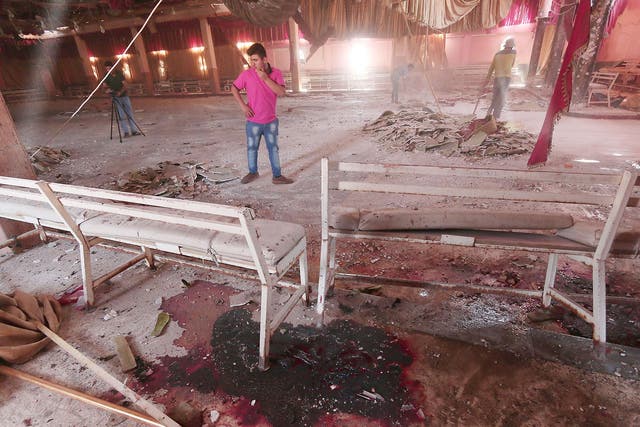 Blood stains the ground while workers remove rubble in a damaged wedding hall after a suicide attack on a Kurdish wedding in Hasaka city, Syria