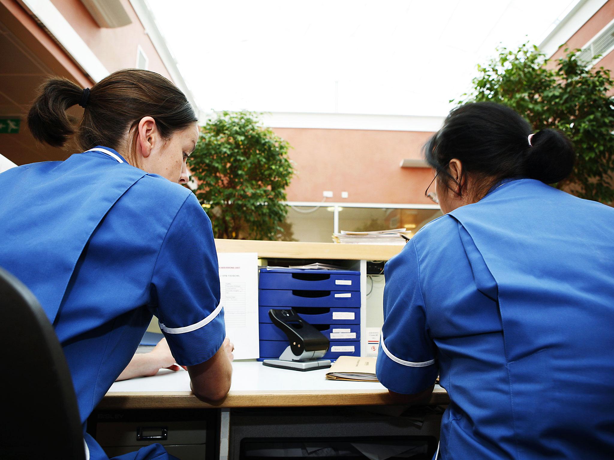 Two nurses sitting behind reception desk in London hospital