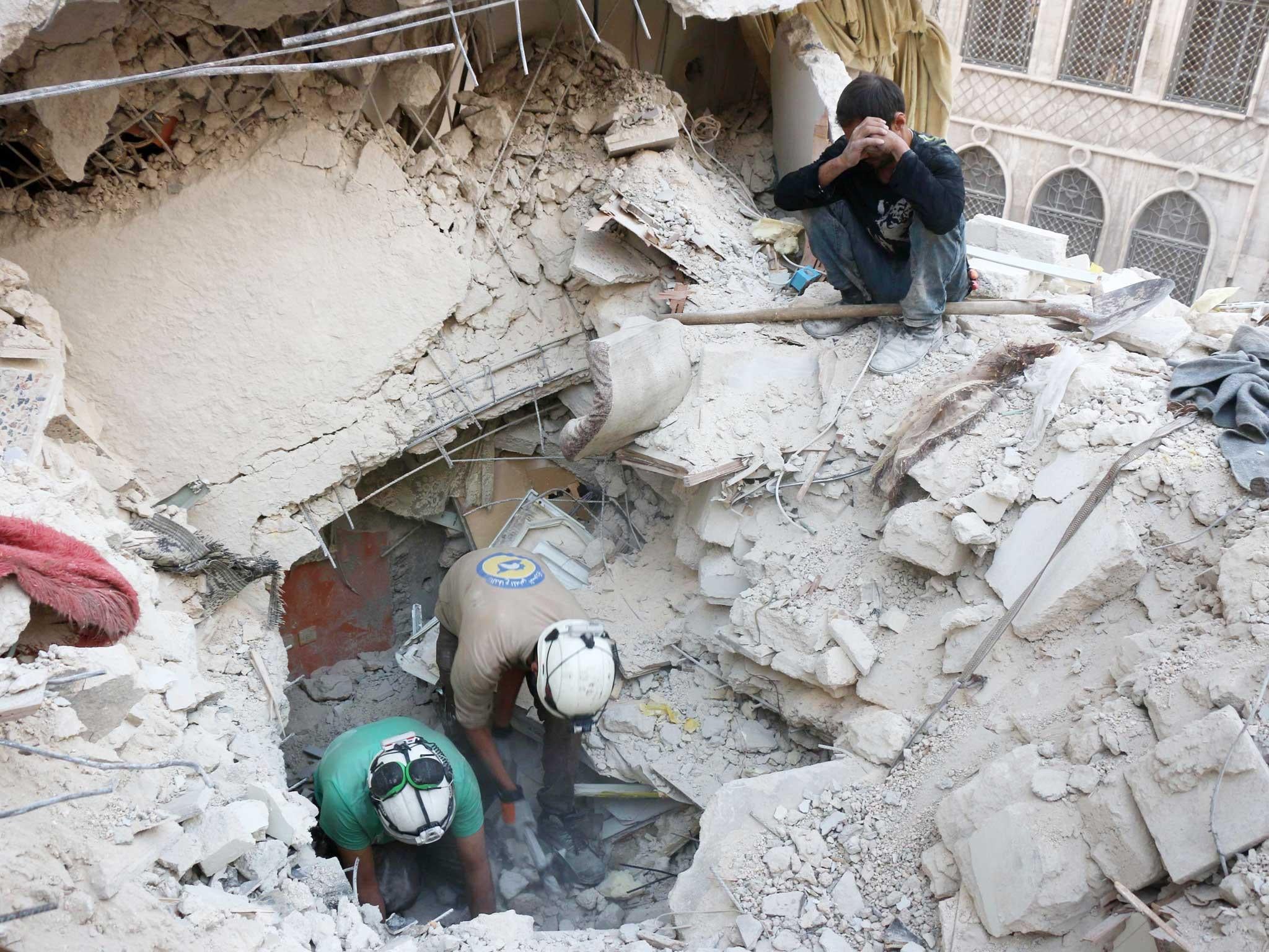 Syrian civil defence volunteers, known as the White Helmets, search for victims amid the rubble of destroyed buildings following a government forces air strike on the rebel-held neighbourhood of Bustan al-Basha in the northern city of Aleppo