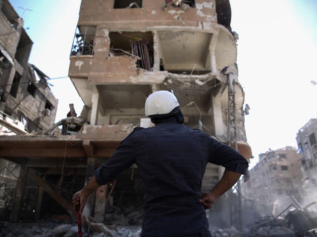 A member of the Syrian civil defence volunteers, known as the White Helmets, looks at a destroyed building following a reported air strike on the rebel-held town of Douma, on the eastern outskirts of the capital Damascus yesterday