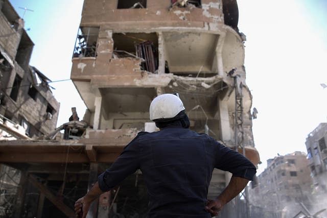 A member of the Syrian civil defence volunteers, known as the White Helmets, looks at a destroyed building following a reported air strike on the rebel-held town of Douma, on the eastern outskirts of the capital Damascus yesterday