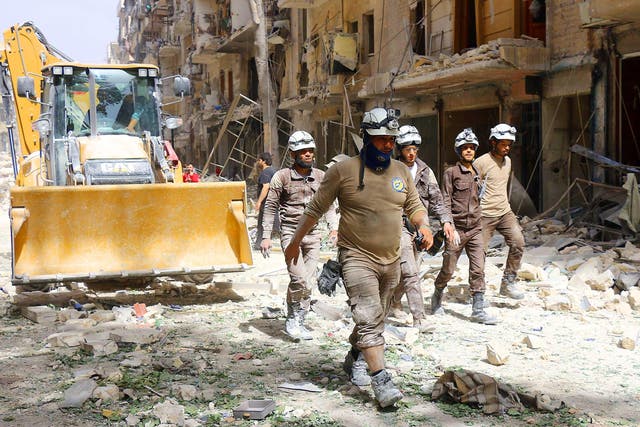 Syrian civil defence volunteers, known as the White Helmets, walk amidst the debris following a reported air strike by Syrian government forces in the rebel-held neighbourhood of Sukkari in the northern city of Aleppo