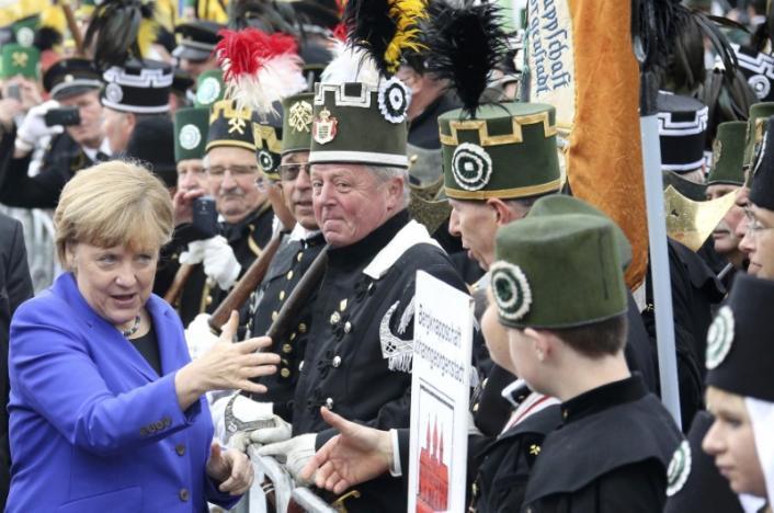 Angela Merkel greets miners' association members during celebrations marking the German Unification Day in Dresden – Reuters