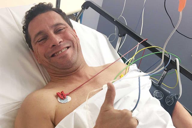 Steven Woolfe lies in a hospital bed with Thumbs-up