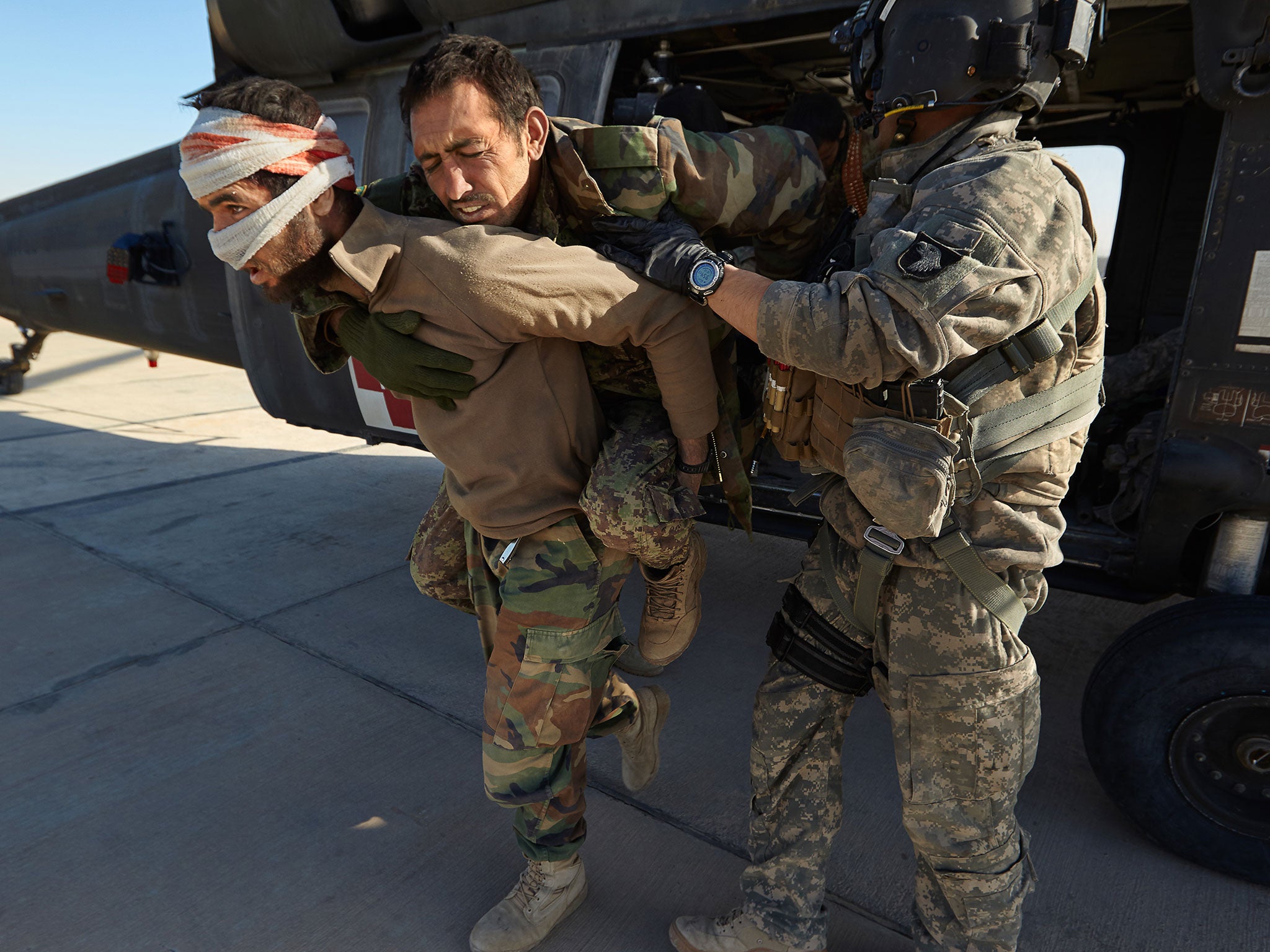 US Army Sargeant Jay Kenney (right), with Task Force Destiny, helps wounded Afghan National Army soldiers exit a Blackhawk helicopter after they have been rescued in an air mission. (Kandahar, December 12, 2010)