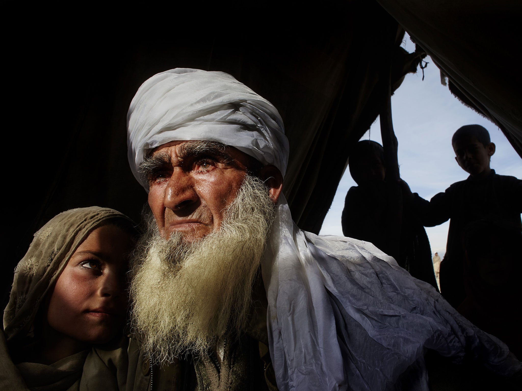 An elderly man holds his granddaughter in their tent at a refugee camp after they were forced to flee their village, which US and NATO forces had bombed because, they claimed, it was a Taliban hideout. (Surobi, Nangarhar Province, February 7, 2009)
