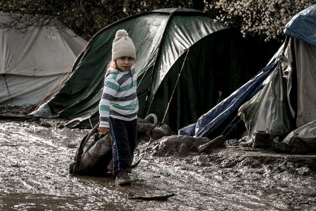Unaccompanied refugee children walk among the shelters at the Jungle camp at Calais