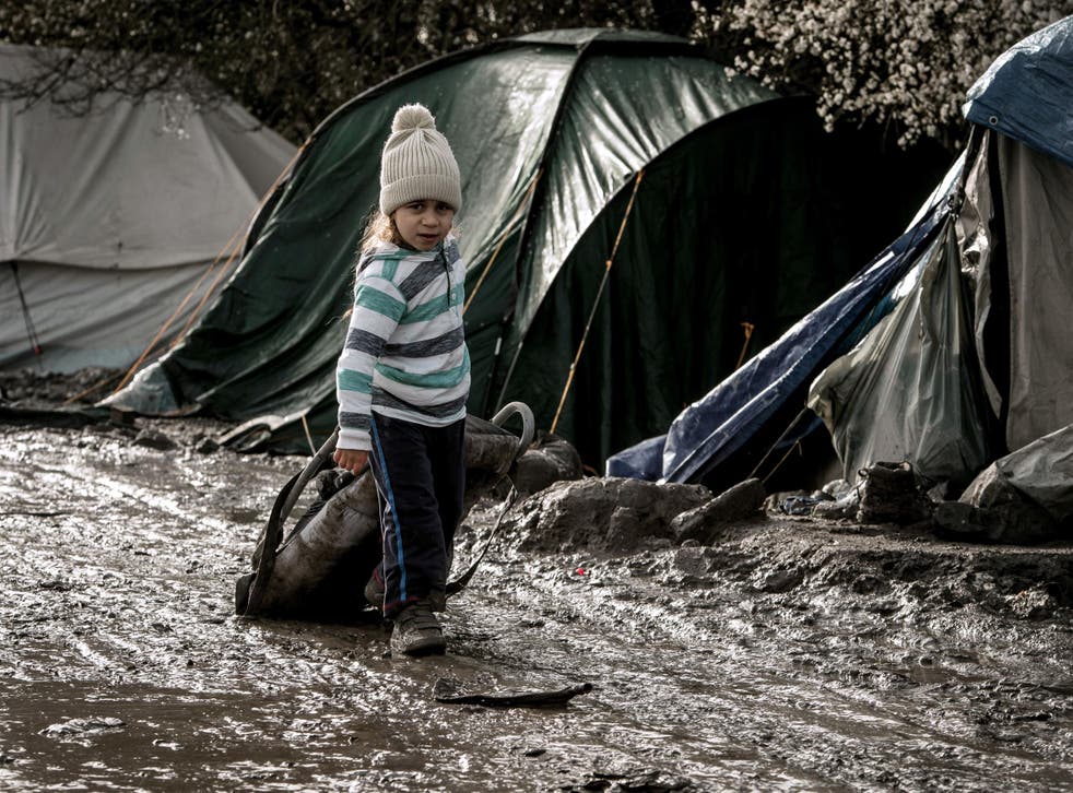 Unaccompanied refugee children walk among the shelters at the Jungle camp at Calais